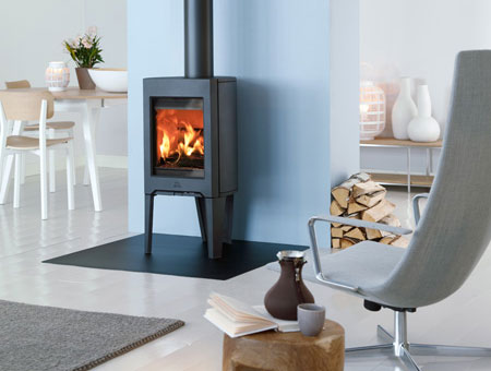 Jotul F 162 wood burning stove in room with log pile at side